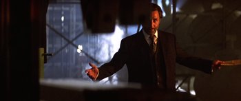 Movie still from “Timecop” (1994), directed by Peter Hyams – A man in a suit and tie pointing to the side; Medium shot, Low angle