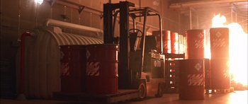 Movie still from “Timecop” (1994), directed by Peter Hyams – A fork lift is parked next to a large stack of barrels; Wide shot, Low angle