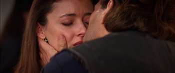 Movie still from “Timecop” (1994), directed by Peter Hyams – A person kissing another person on the cheek; Extreme Close Up shot, Over the shoulder angle