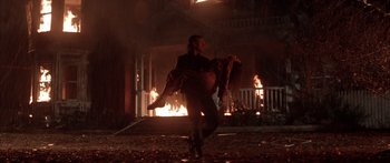Movie still from “Timecop” (1994), directed by Peter Hyams – A man carrying a woman through a burning house; Wide shot, Low angle