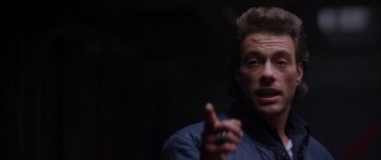 Movie still from “Timecop” (1994), directed by Peter Hyams – A man in a blue jacket is holding a cigarette; Close Up shot, Over the shoulder angle