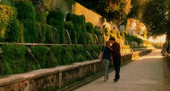 Movie still from “To Rome with Love” (2012), directed by Woody Allen – A man and a woman walking next to each other near a fountain; Wide shot, Over the shoulder angle
