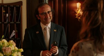 Movie still from “To Rome with Love” (2012), directed by Woody Allen – A man in a suit and tie holding a cell phone; Medium shot, Over the shoulder angle