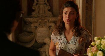 Movie still from “To Rome with Love” (2012), directed by Woody Allen – A woman holding a purse in front of a wall; Close Up shot, Over the shoulder angle