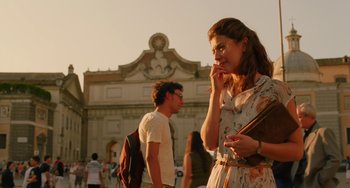 Movie still from “To Rome with Love” (2012), directed by Woody Allen – A woman is standing in front of a man while holding a cell phone to her ear; Medium shot, Over the shoulder angle