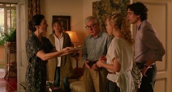 Movie still from “To Rome with Love” (2012), directed by Woody Allen – A group of people standing around each other in a living room; Medium shot, Over the shoulder angle
