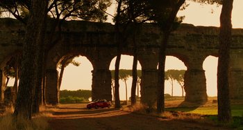 Movie still from “To Rome with Love” (2012), directed by Woody Allen – A car driving on a dirt road under a bridge; Extreme Wide shot, Low angle