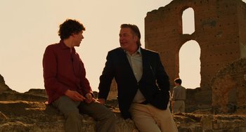Movie still from “To Rome with Love” (2012), directed by Woody Allen – Two men are sitting on a wall and talking to each other; Medium shot, Over the shoulder angle
