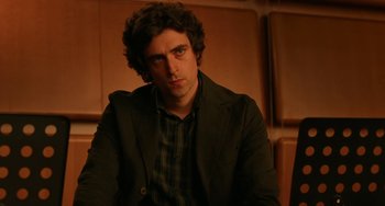 Movie still from “To Rome with Love” (2012), directed by Woody Allen – A man in a black jacket is sitting down; Close Up shot, Low angle