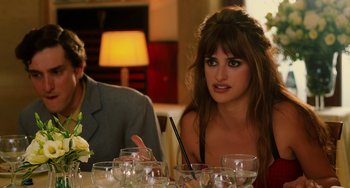 Movie still from “To Rome with Love” (2012), directed by Woody Allen – A woman sitting at a table with a man in the background; Close Up shot, Over the shoulder angle