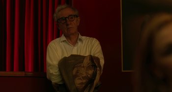 Movie still from “To Rome with Love” (2012), directed by Woody Allen – An older man holding a suit jacket in front of a red curtain; Medium shot, Over the shoulder angle
