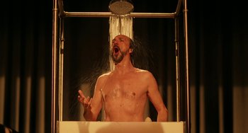 Movie still from “To Rome with Love” (2012), directed by Woody Allen – A man is taking a shower in a bath tub; Medium shot, Low angle