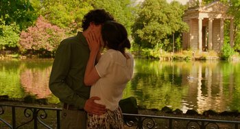 Movie still from “To Rome with Love” (2012), directed by Woody Allen – A man and a woman kissing in front of a body of water; Medium shot, Low angle