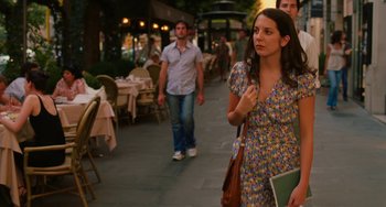 Movie still from “To Rome with Love” (2012), directed by Woody Allen – A group of people walking down a sidewalk near tables; Medium shot, Over the shoulder angle