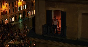 Movie still from “To Rome with Love” (2012), directed by Woody Allen – A man standing on a balcony looking out of a window; Extreme Wide shot, High angle