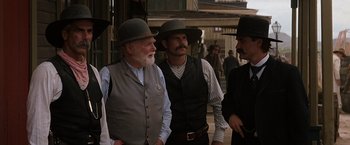 Movie still from “Tombstone” (1993), directed by George P. Cosmatos – A group of men standing next to each other on a street; Medium shot, Over the shoulder angle