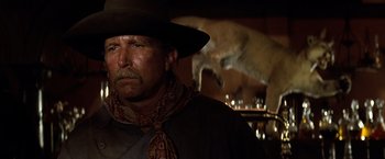 Movie still from “Tombstone” (1993), directed by George P. Cosmatos – A man in a cowboy hat with a fox in the background; Close Up shot, Low angle