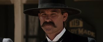Movie still from “Tombstone” (1993), directed by George P. Cosmatos – A person wearing a suit and a hat; Close Up shot, Low angle