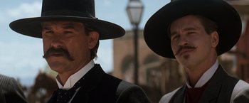 Movie still from “Tombstone” (1993), directed by George P. Cosmatos – A man and a woman in black hats and suits; Close Up shot, Low angle