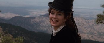 Movie still from “Tombstone” (1993), directed by George P. Cosmatos – A woman in a top hat smiling for the camera; Close Up shot, Low angle