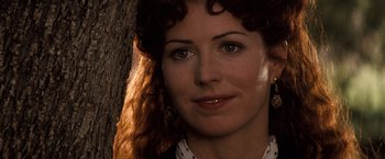 Movie still from “Tombstone” (1993), directed by George P. Cosmatos – A woman's face in front of a tree; Close Up shot, Over the shoulder angle