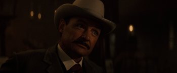 Movie still from “Tombstone” (1993), directed by George P. Cosmatos – A person wearing a suit and a hat; Close Up shot, Low angle