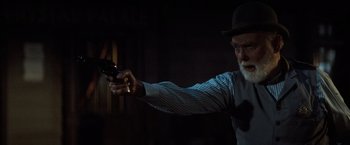 Movie still from “Tombstone” (1993), directed by George P. Cosmatos – An older man holding a gun in a dark room; Close Up shot, Over the shoulder angle