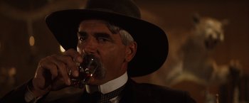 Movie still from “Tombstone” (1993), directed by George P. Cosmatos – An older man wearing a hat and drinking a glass of wine; Close Up shot, Low angle