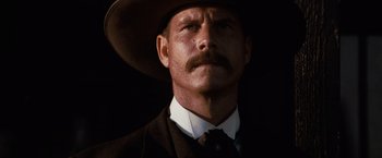 Movie still from “Tombstone” (1993), directed by George P. Cosmatos – A person wearing a suit and a hat; Close Up shot, Low angle