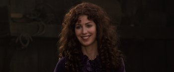 Movie still from “Tombstone” (1993), directed by George P. Cosmatos – A woman with long curly brown hair smiling for the camera; Close Up shot, Over the shoulder angle