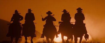 Movie still from “Tombstone” (1993), directed by George P. Cosmatos – Three men on horseback are silhouetted against the setting sun; Wide shot, Low angle