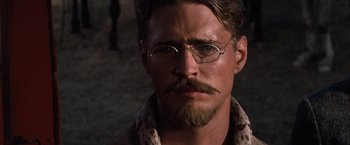 Movie still from “Tombstone” (1993), directed by George P. Cosmatos – A man with glasses and a mustache wearing glasses; Close Up shot, Low angle