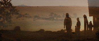 Movie still from “Tombstone” (1993), directed by George P. Cosmatos – A man standing on top of a dirt field; Extreme Wide shot, Over the shoulder angle