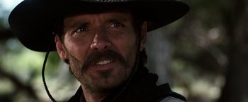 Movie still from “Tombstone” (1993), directed by George P. Cosmatos – A person wearing a cowboy hat; Close Up shot, Over the shoulder angle