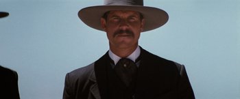 Movie still from “Tombstone” (1993), directed by George P. Cosmatos – A person wearing a suit and a hat; Close Up shot, Low angle