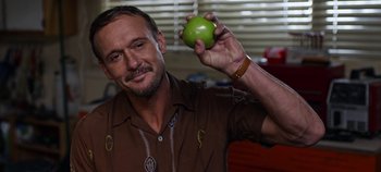 Movie still from “Tomorrowland” (2015), directed by Brad Bird – A man holding an apple in his right hand; Close Up shot, Over the shoulder angle