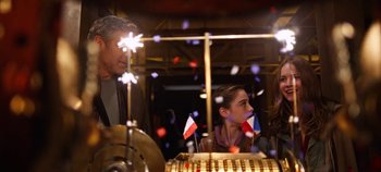 Movie still from “Tomorrowland” (2015), directed by Brad Bird – A man and a woman sitting next to each other in front of fireworks; Medium shot, Over the shoulder angle