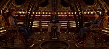 Movie still from “Tomorrowland” (2015), directed by Brad Bird – A man sitting on a chair in a room; Wide shot, High angle