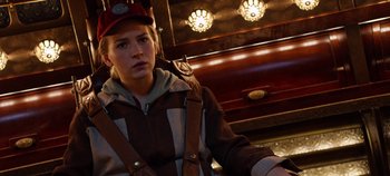Movie still from “Tomorrowland” (2015), directed by Brad Bird – A woman wearing a hat and a brown jacket standing in front of a fireplace; Close Up shot, Over the shoulder angle