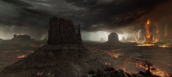 Movie still from “Tomorrowland” (2015), directed by Brad Bird – A desert landscape with a rock formation in the foreground and dark clouds in the background; Extreme Wide shot, High angle