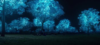 Movie still from “Tomorrowland” (2015), directed by Brad Bird – A group of people sitting under a tree at night; Extreme Wide shot, Low angle