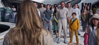 Movie still from “Tomorrowland” (2015), directed by Brad Bird – A group of people standing around a woman; Medium shot, Over the shoulder angle