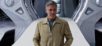 Movie still from “Tomorrowland” (2015), directed by Brad Bird – A man in a tan jacket standing next to a white wall; Medium shot, Low angle