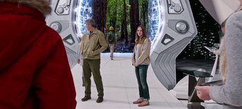 Movie still from “Tomorrowland” (2015), directed by Brad Bird – A man and a woman standing in front of an entrance to a forest; Medium shot, Over the shoulder angle