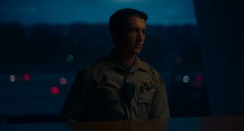Movie still from “Too Old to Die Young” (2019), directed by Nicolas Winding Refn – A man in a police uniform standing in front of a window at night; Medium shot, Low angle