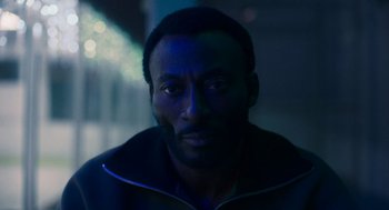 Movie still from “Too Old to Die Young” (2019), directed by Nicolas Winding Refn – A man with a black jacket is looking at the camera; Close Up shot, Over the shoulder angle