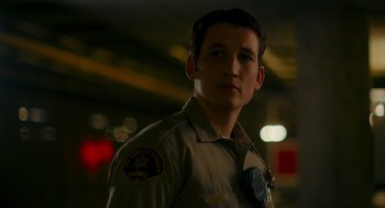 Movie still from “Too Old to Die Young” (2019), directed by Nicolas Winding Refn – A man in a police uniform standing in a parking lot; Close Up shot, Over the shoulder angle