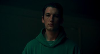 Movie still from “Too Old to Die Young” (2019), directed by Nicolas Winding Refn – A man in a green hoodie is in a dark room; Close Up shot, Low angle