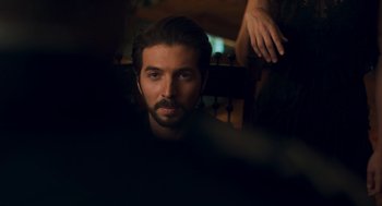 Movie still from “Too Old to Die Young” (2019), directed by Nicolas Winding Refn – A man with long hair and a goatee stares into the camera; Close Up shot, Over the shoulder angle
