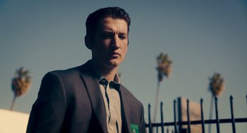 Movie still from “Too Old to Die Young” (2019), directed by Nicolas Winding Refn – A man in a suit and tie standing in front of a palm tree; Close Up shot, Low angle